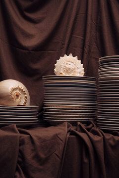 Still life composition with stacked ceramic plates,  seashells