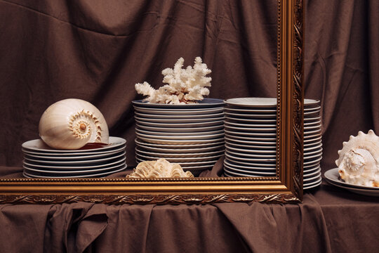 Still life composition with stacked ceramic plates,  seashells