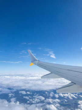 Airplane wing soaring high above the clouds in a blue sky