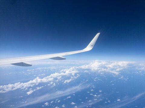 Airplane wing flying above clouds on sunny day