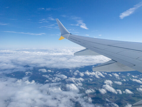 Airplane wing flying above clouds on sunny day
