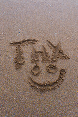 Abbreviated thank you message with smiley face drawn in the sand