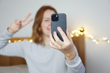 Young woman making a video call on a smartphone camera, showing emotions
