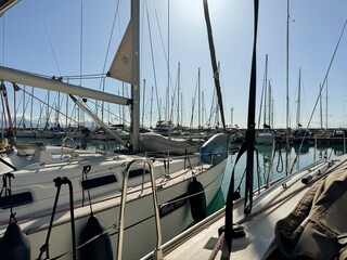 Sailboats docked in a marina under a bright sun during midday