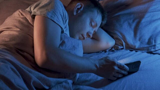 Caucasian man fall asleep in bed at home using mobile phone. Tired, exhausted male sleeping with smartphone in bedroom. Smartphone, internet, social media, gadget addiction concept