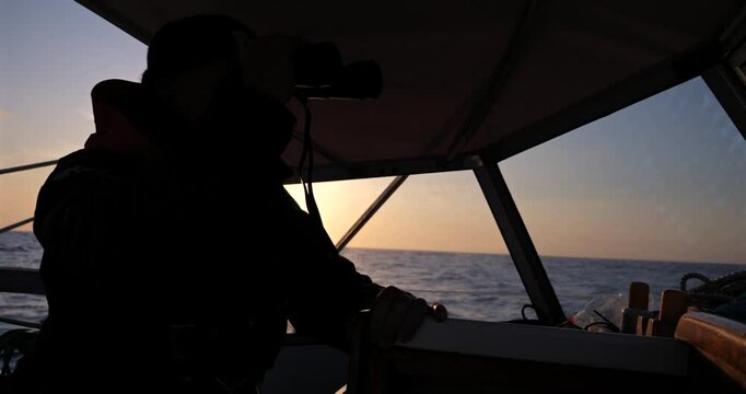 Silhuete of sailor looking trough binoculars from his sailboat and over the on the Bay of Biscay Stock
