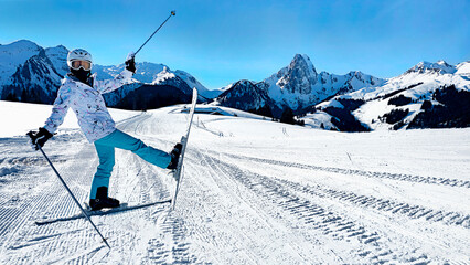 A cheerful skier posing on a snowy ski trail with majestic Alpine mountains in the background.