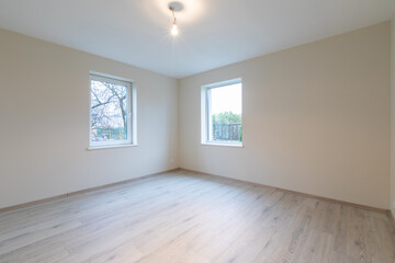 Modern New Construction Empty Room With Wooden Flooring and Large Windows Allowing Natural Light. Home Interior