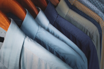 close-up of mens long sleeve dress shirts collars work lined up in a row on wooden hangers home...