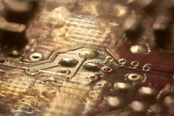 Electronic circuit board showing tracks, resistors, and capacitors in golden light