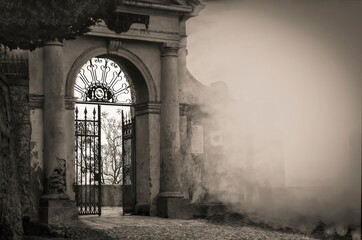 Old cemetery gates opening into fog on a spooky day