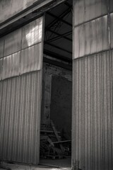 Old abandoned industrial building with open sliding door revealing interior