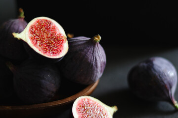 Close up of fresh ripe fig fruits in a wooden bowl on dark grey table 