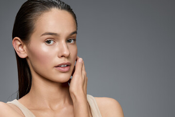 Natural beauty portrait of a young woman with sleek hair and a soft expression, highlighting healthy skin and minimalist style, perfect for wellness themes