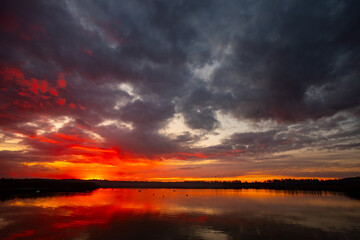 A Stunning Sunset Over a Tranquil Lake Surrounded by Dramatic and Colorful Skies
