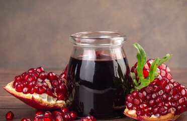 Glass bottle of pomegranate sour sauce with fresh ripe whole and split pomegranate fruit (Turkish...