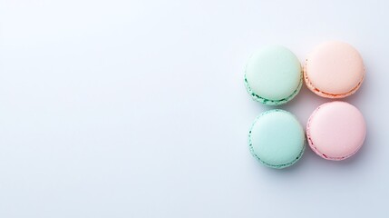 Obraz premium Four pastel macarons, minimalistic dessert arrangement, light blue background, French confectionery, elegant food styling, flat lay composition, colorful sweets