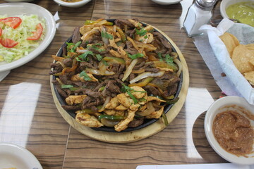 Parillada of chicken and meat fajitas on a skillet.