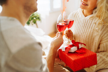 Happy couple drinking red wine at home. Romantic day together. Leisure, celebration and Valentine’s Day concept.