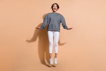 Full length photo of good mood impressed girl wear pullover white trousers jumping staring at sale...