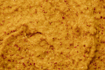 Mustard sauce with grains close-up. Hot spices as a background. Texture of Dijon mustard.