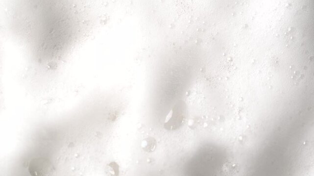 Hair foam mousse rotation, macro. Beauty background. Close up of white cloud of hair mousse or shaving foam. Soap suds