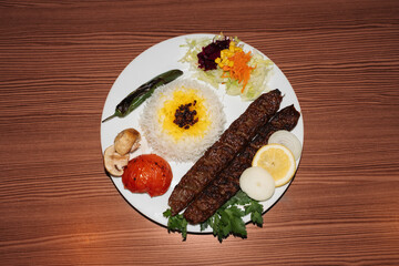 Turkish kebab plate with rice and salad on wooden background. Retro flash food photography