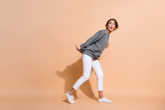 Full size photo of astonished woman dressed grey pullover pull object staring at offer empty space isolated on pastel color background