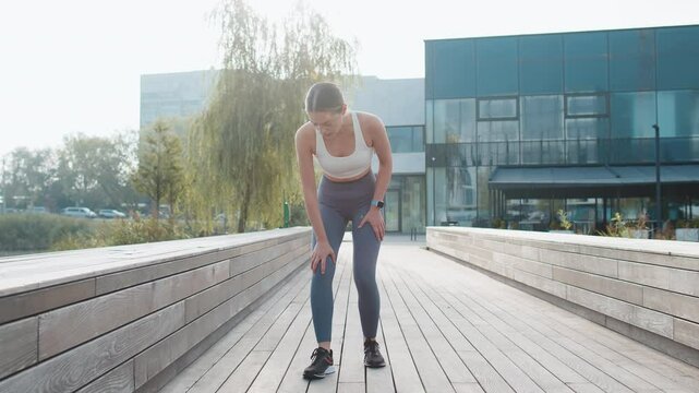 Athletic fit runner girl with muscle pain. Young woman massaging stretching, trauma injury while jogging outdoors in city park. Fitness female sprain severe pain stretch pull. Leg muscle cramp calf.