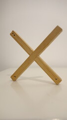 Wooden wall-mounted cross on a neutral background.
