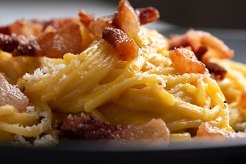 Primo piano di deliziosi spaghetti alla carbonara, ricetta tipica di pasta della cucina romana,...