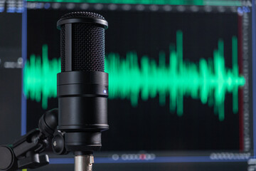 Professional studio microphone with a green audio waveform on a monitor in the background, podcast...