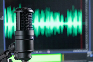 Professional studio microphone with a green audio waveform on a monitor, recording and podcast...
