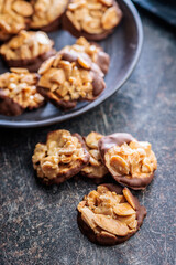 Photography of chocolate Florentines cookies with almonds and chocolate on black table.