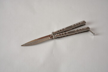 Silver butterfly knife with a sleek, metallic handle on a plain background.