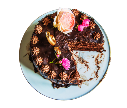Top view of luxurious chocolate layer cake decorated with roses and intricate details, partially eaten. Glass plate with birthday cake with floral decorations and a slice removed. Copy space