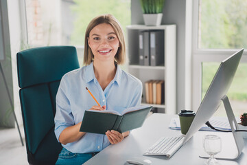 Photo of attractive young corporate woman pencil notebook computer desk wear blue shirt modern office indoors