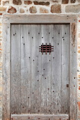 Mont-Saint-Michel: Old unpainted, studded wood door with grating peephole on the Loop Bastion-Tour Boucle Tower building SE side. Normandy-France-172