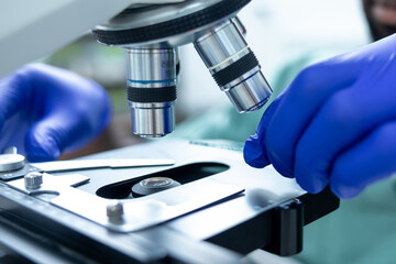 Medical man working in lab using microscope for analysis of virus testing and vaccine