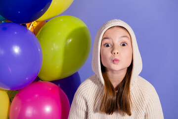 Cute preteen girl making a playful expression with balloons