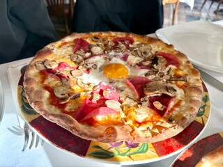 Egg Capricciosa pizza with cheese, bacon, tomatoes, mushrooms and basil, italian meal.