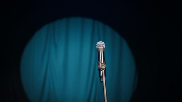 Open mic in nightclub or comedy club, possibility for expression of talents. Microphone on stand against blue curtains in bright soffit lights, stage of theatre or concert hall, nobody, wait for start
