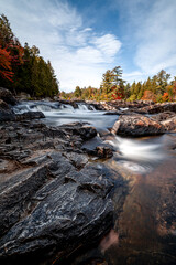 Autumn waterfall scenery with fallen leaves and beautiful fall colors at national park de la Mauricie