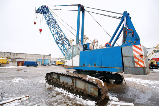 Crawler crane at construction worksite during winter, heavy machinery for industrial lifting and engineering projects. Heavy duty crawler crane with hydraulic boom at industrial site, construction