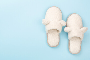 Soft teddy slippers on color background, top view