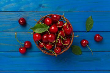 Fresh cherries in bowl on wooden background, top view