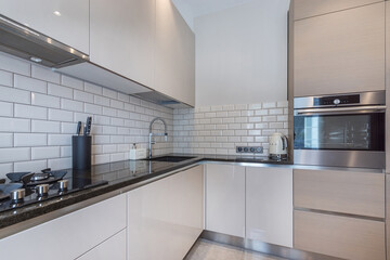 Modern design of the kitchen, decorated in pastel colors. Granite countertop, built-in appliances, stylish accessories.