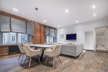 The living room is decorated in two styles - modern and loft. Brick wall with metal heating batteries. Stylish furniture.