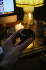 Close-up of hand in tea ritual with soft candlelight
