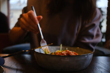 Woman’s hand with a gourmet meal in a cozy urban cafe